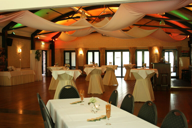 Feestelijk aangeklede zaal met statafels en sfeerverlichting