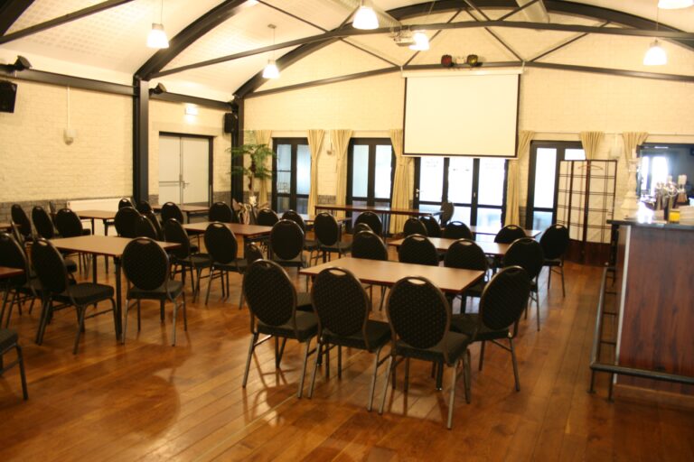 Zaal Houthem met projectiescherm en tafels in schoolopstelling